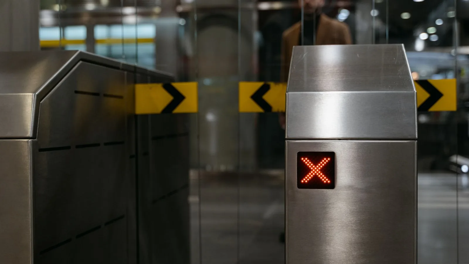 An automatic entrance gate at a subway station showing a lit red X that denies entry.