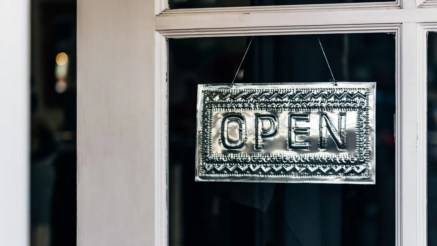 A simple metal Open sign hanging on the door of an independent shop.