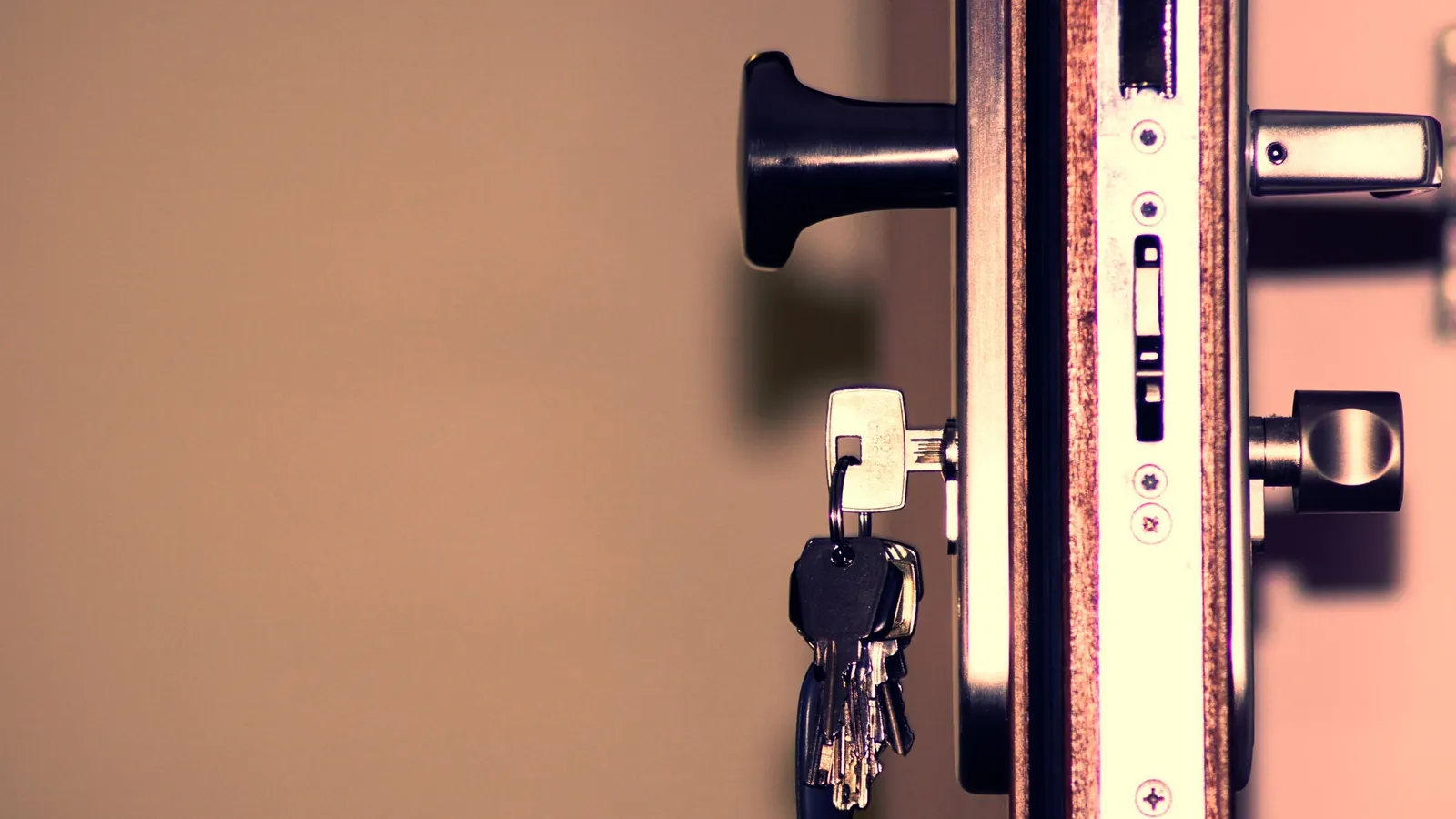 An open door seen edge-on, with a ring of keys left hanging in its lock.